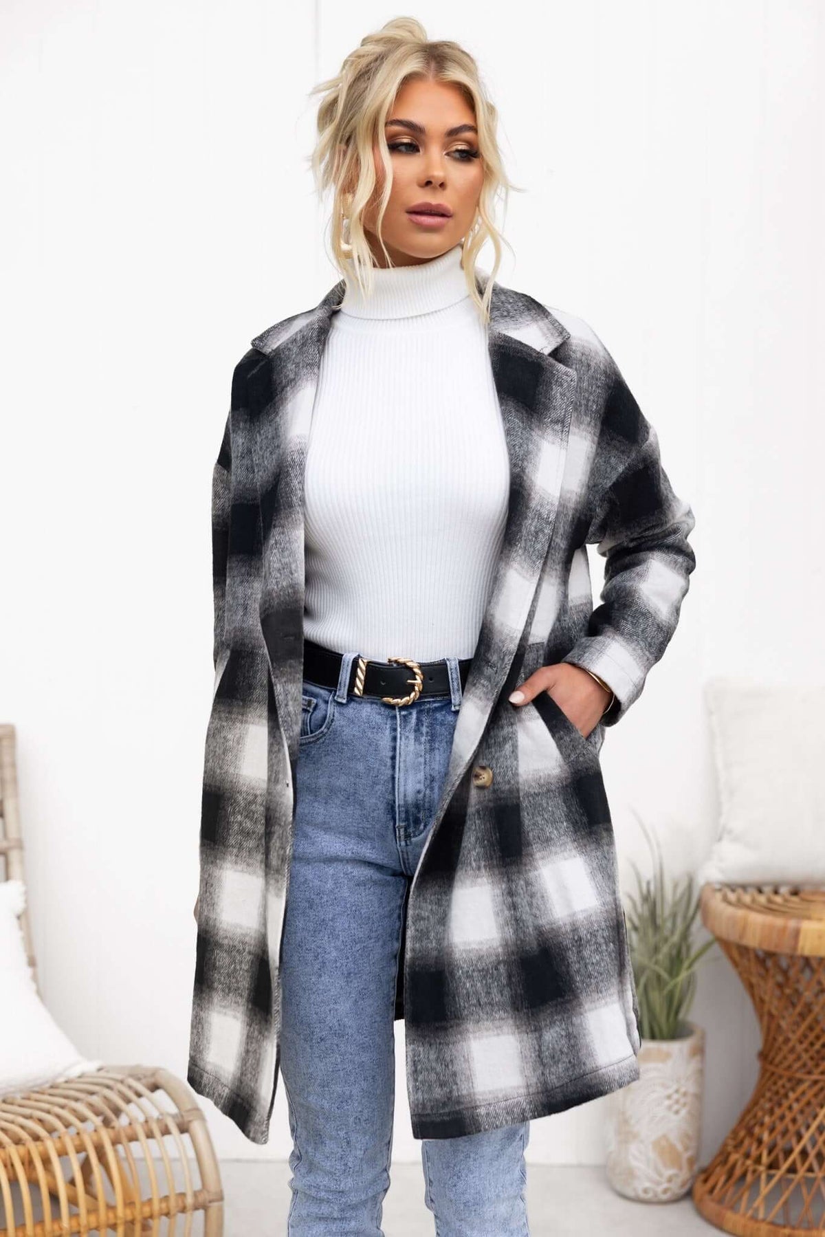 Model wearing a stylish black and white plaid Tiffin coat over a turtleneck, paired with high-waisted jeans.