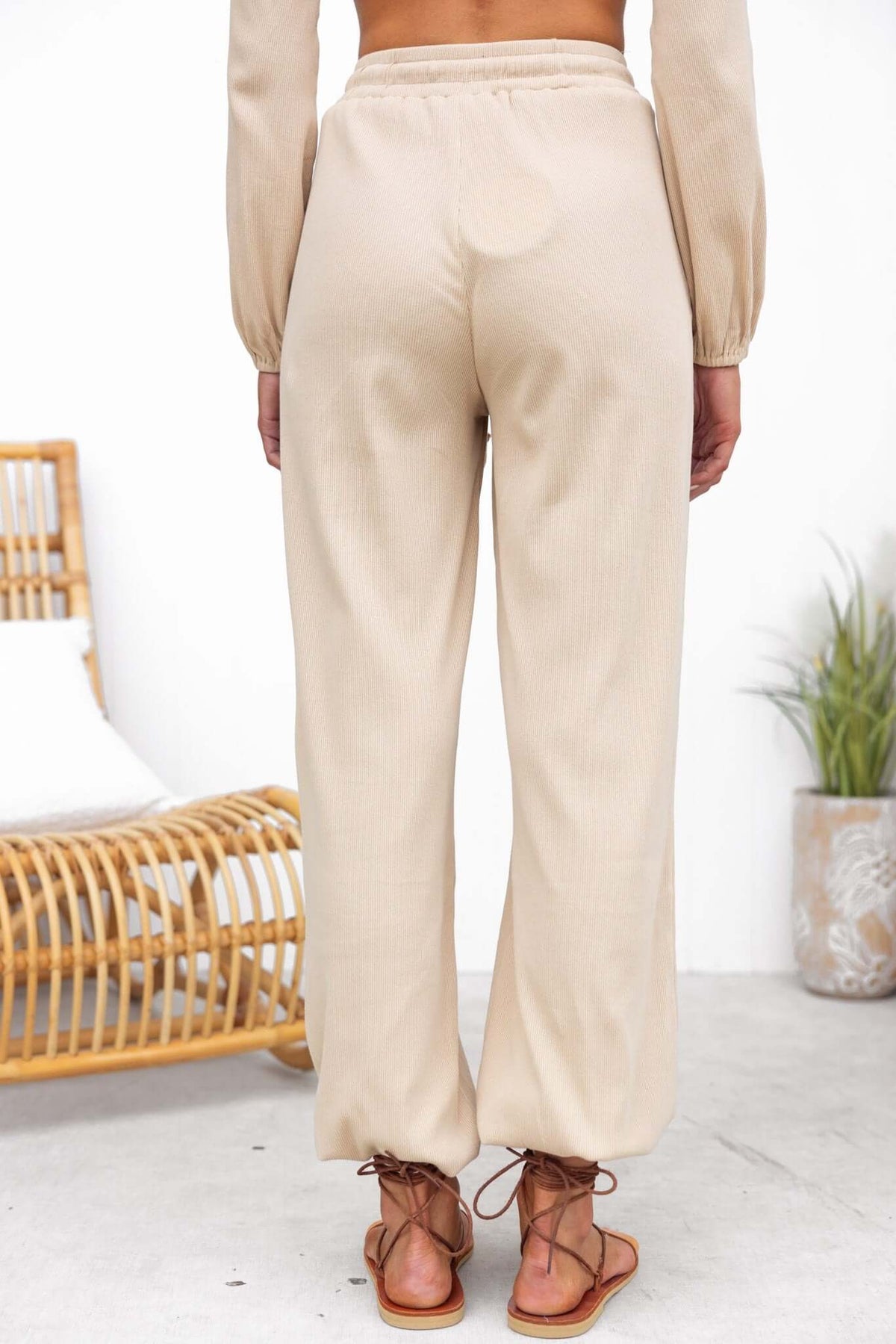 Back view of Micah Pants in beige, featuring mid-high waist, elastic waistband, and cuffs.