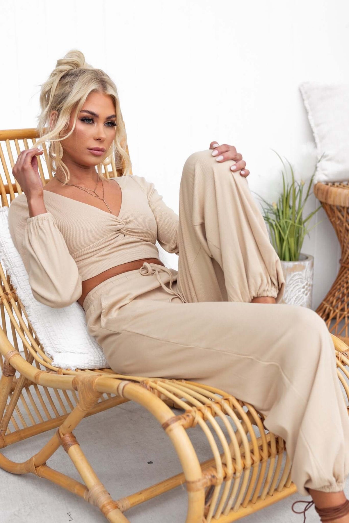 Model in mid-high waist beige Micah Pants with elastic waistband and cuffs, styled in a casual setting.
