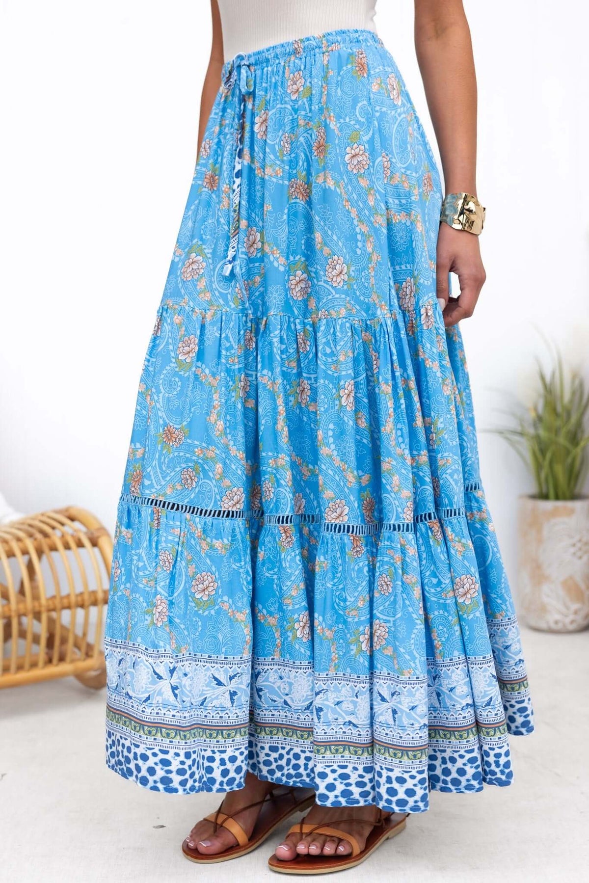 Darian Maxi Skirt in blue floral print with elastic waistband and drawstring, styled with sandals.