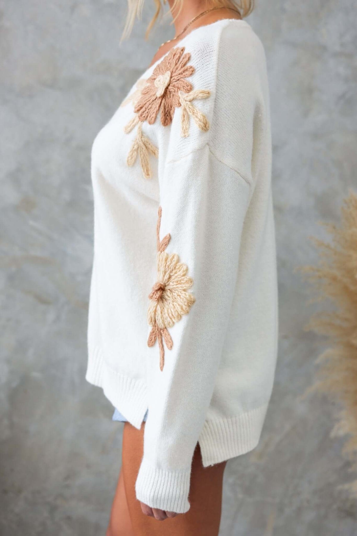 Capa Jumper featuring a V-neckline and floral embroidery in warm tones, displayed by a model against a neutral background.