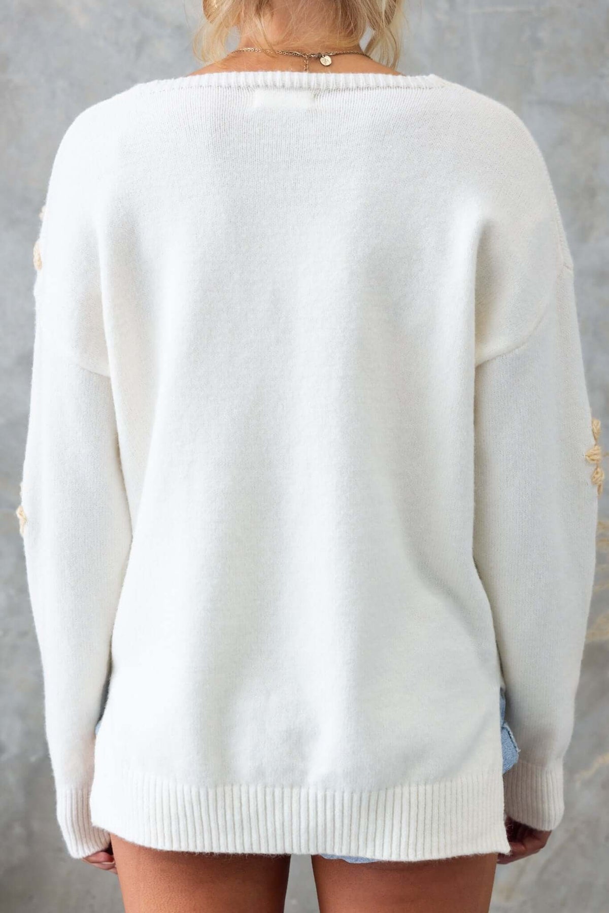 Back view of a white Capa Jumper with side splits, showcasing the knit material and relaxed fit.