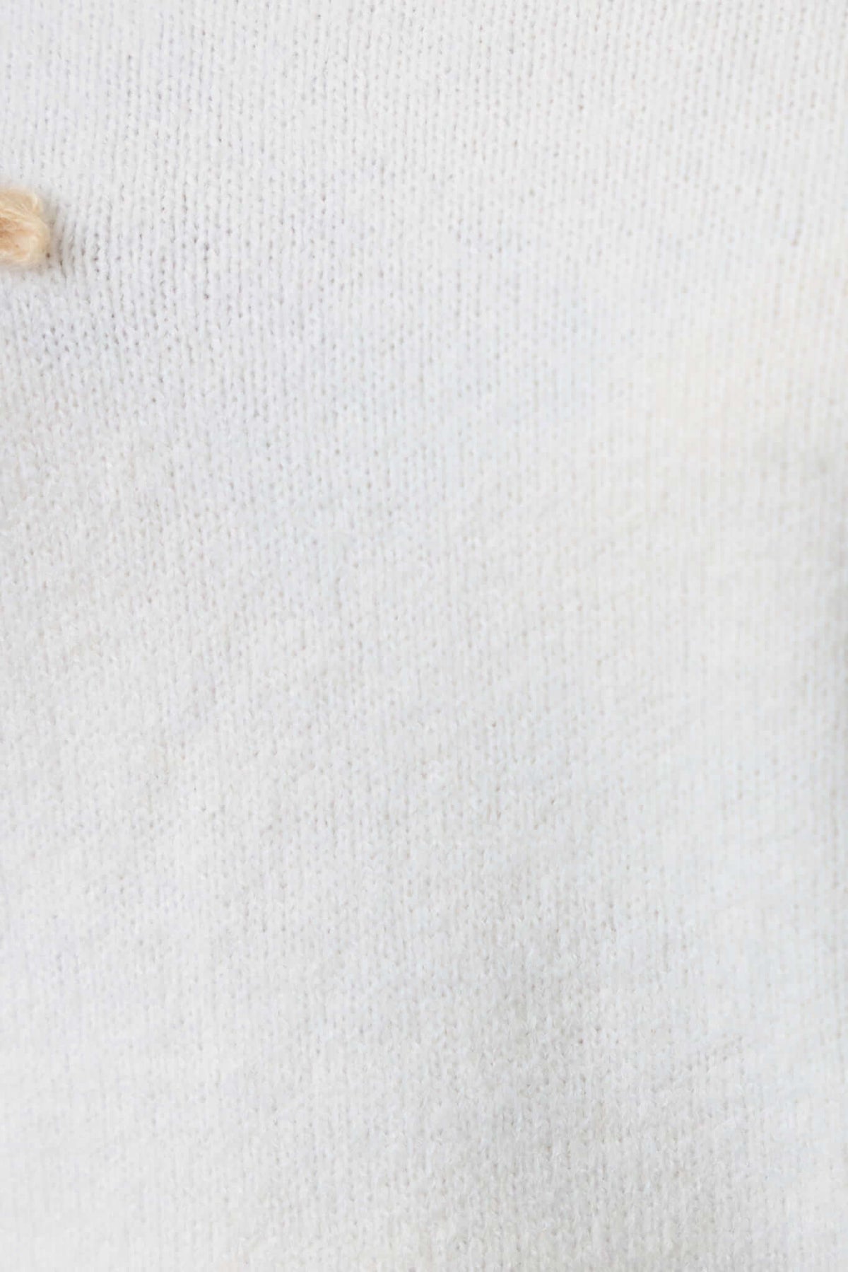 Close-up of a soft white knit material, highlighting the texture of the Capa Jumper.