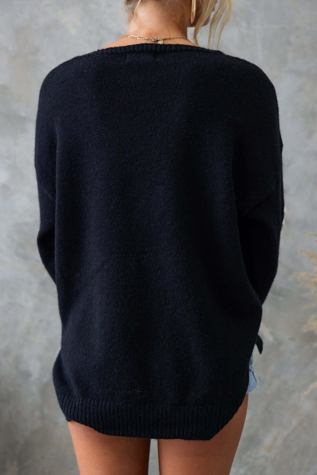 Back view of a black Capa jumper featuring V-neckline and side splits, showcasing a relaxed fit.