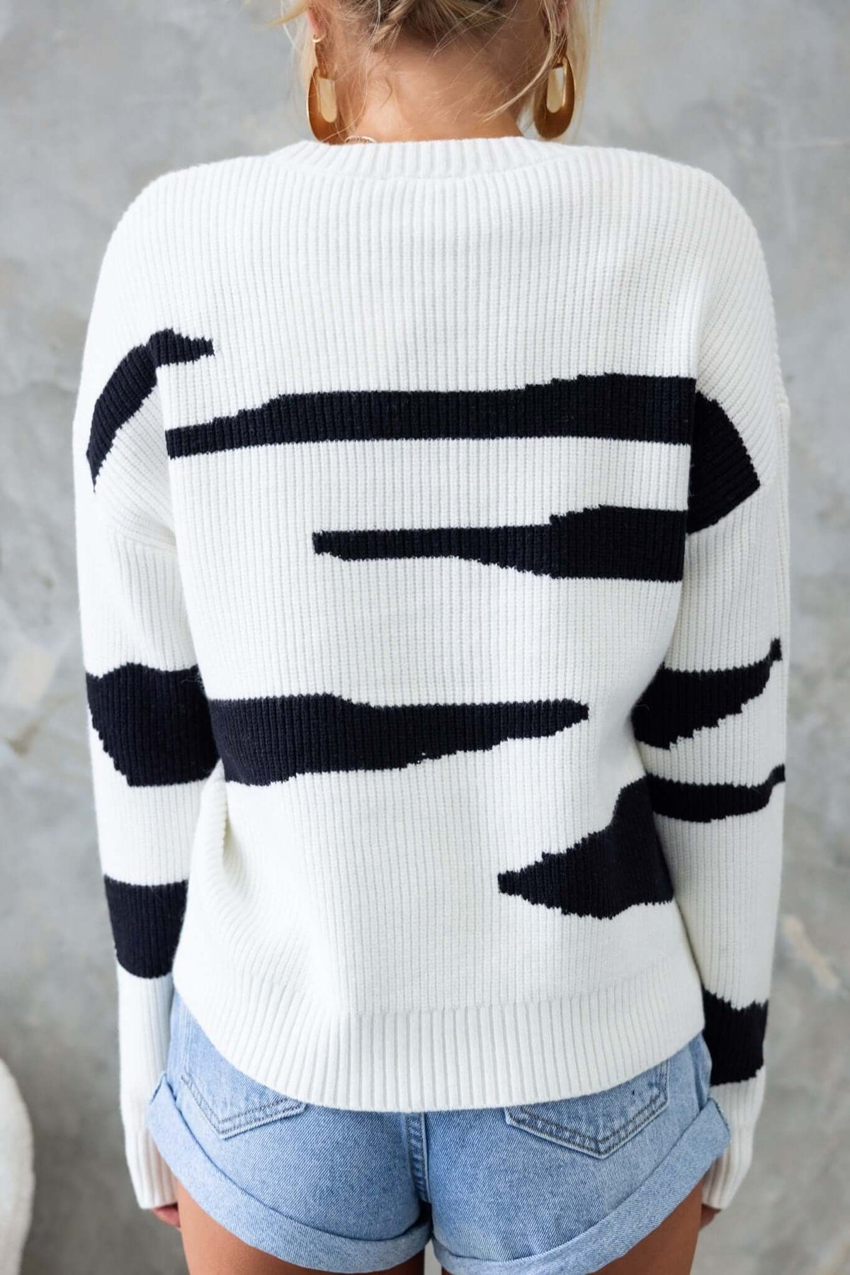 Aiken Jumper featuring a round neckline and ribbed knit design in white and black patterns, paired with denim shorts.