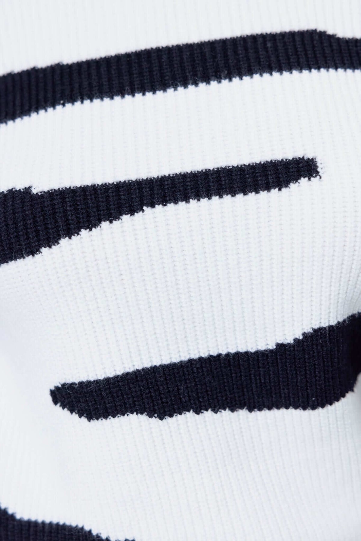 Close-up of Aiken Jumper featuring a ribbed knit pattern in black and white, showcasing its stretchy material.