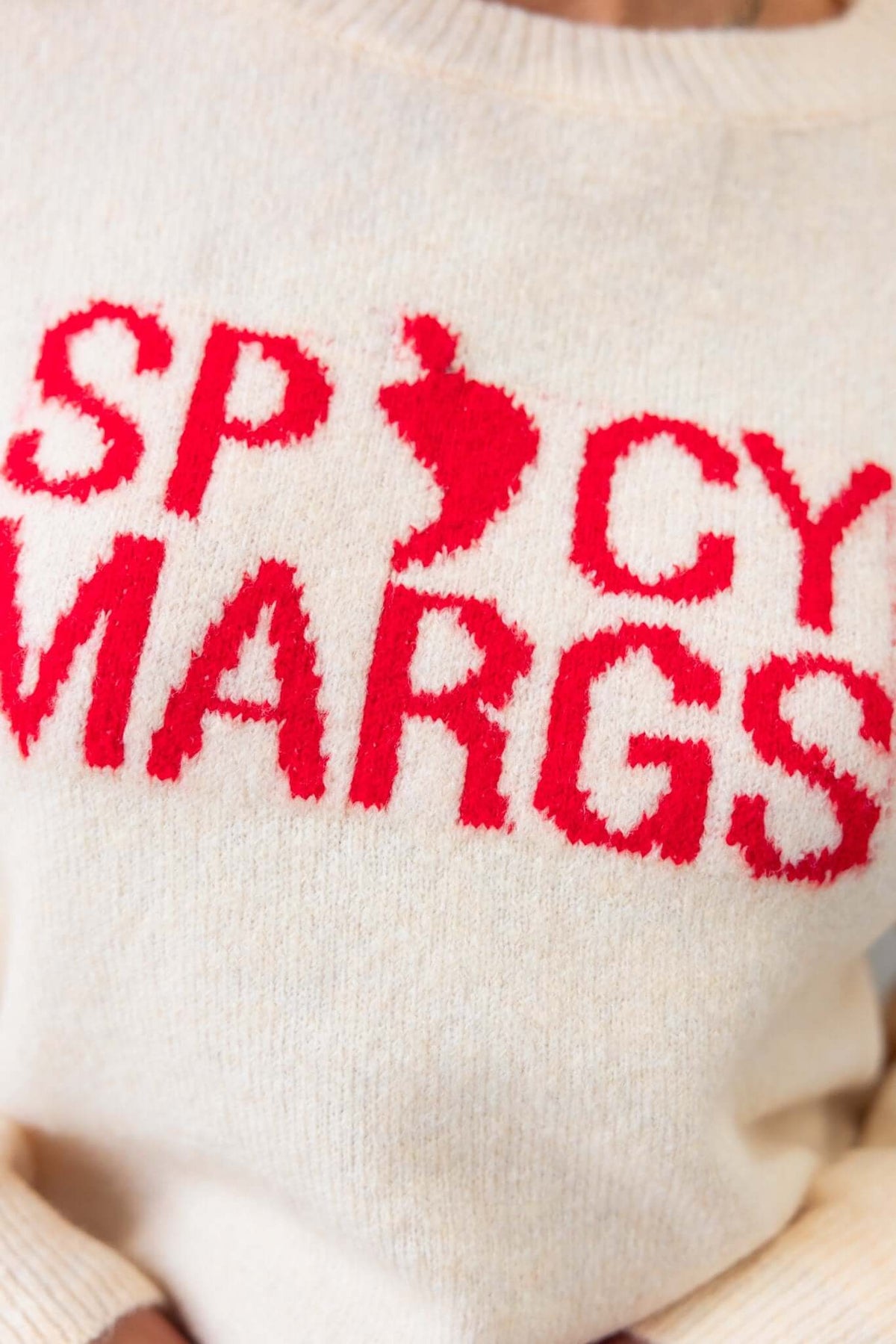Close-up of a cream jumper featuring bold red text reading 'SPICY MARGS' with a playful design, perfect casual wear.