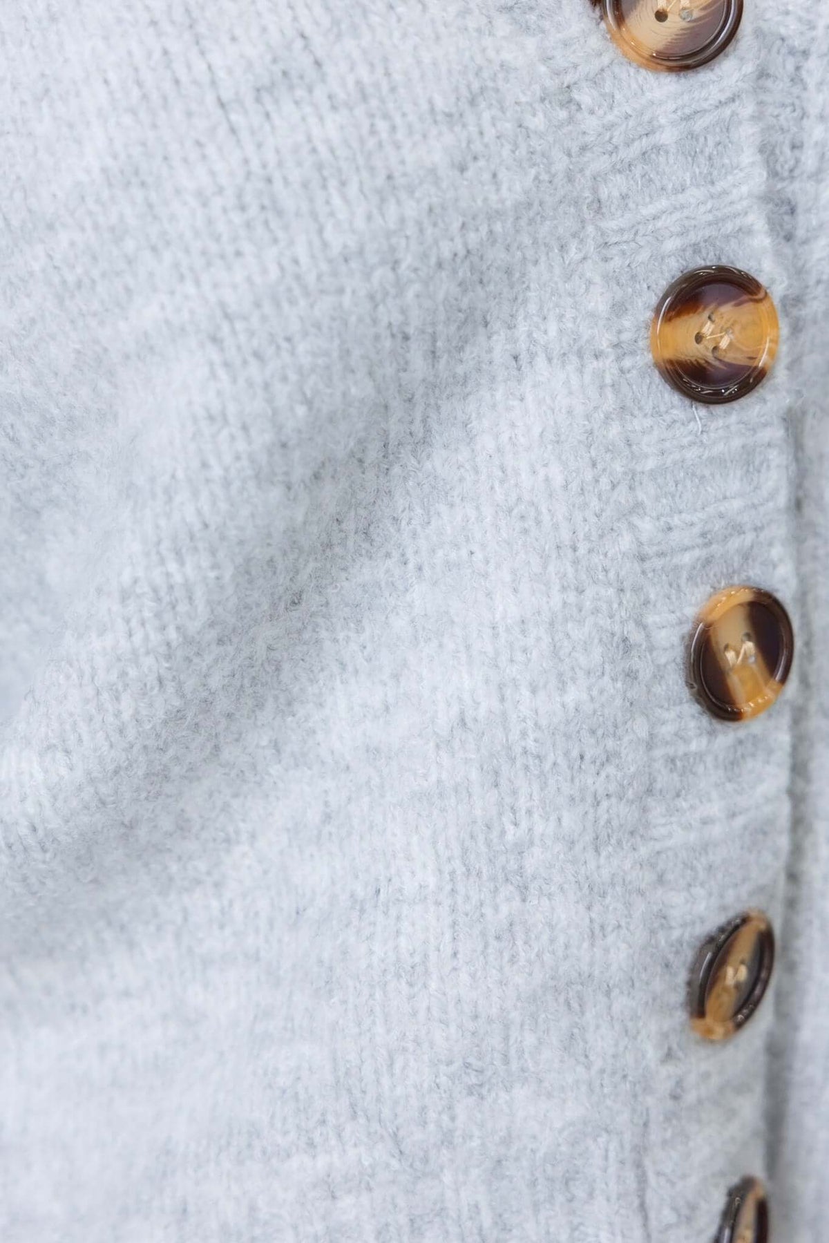 Close-up of Irvine Cardigan buttons and soft knit texture in light gray, showcasing stylish design and quality material.