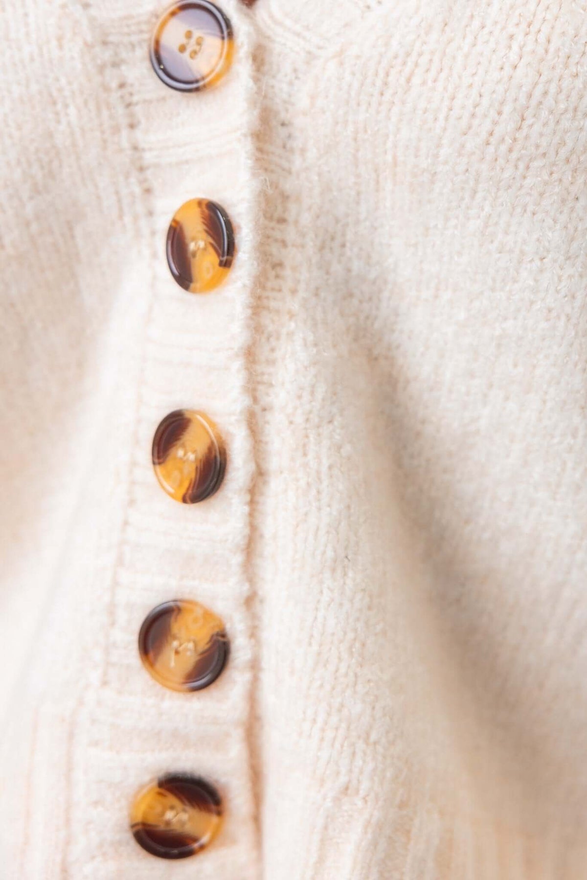 Close-up of Irvine Cardigan's button detail, featuring tortoiseshell buttons on soft knit fabric.