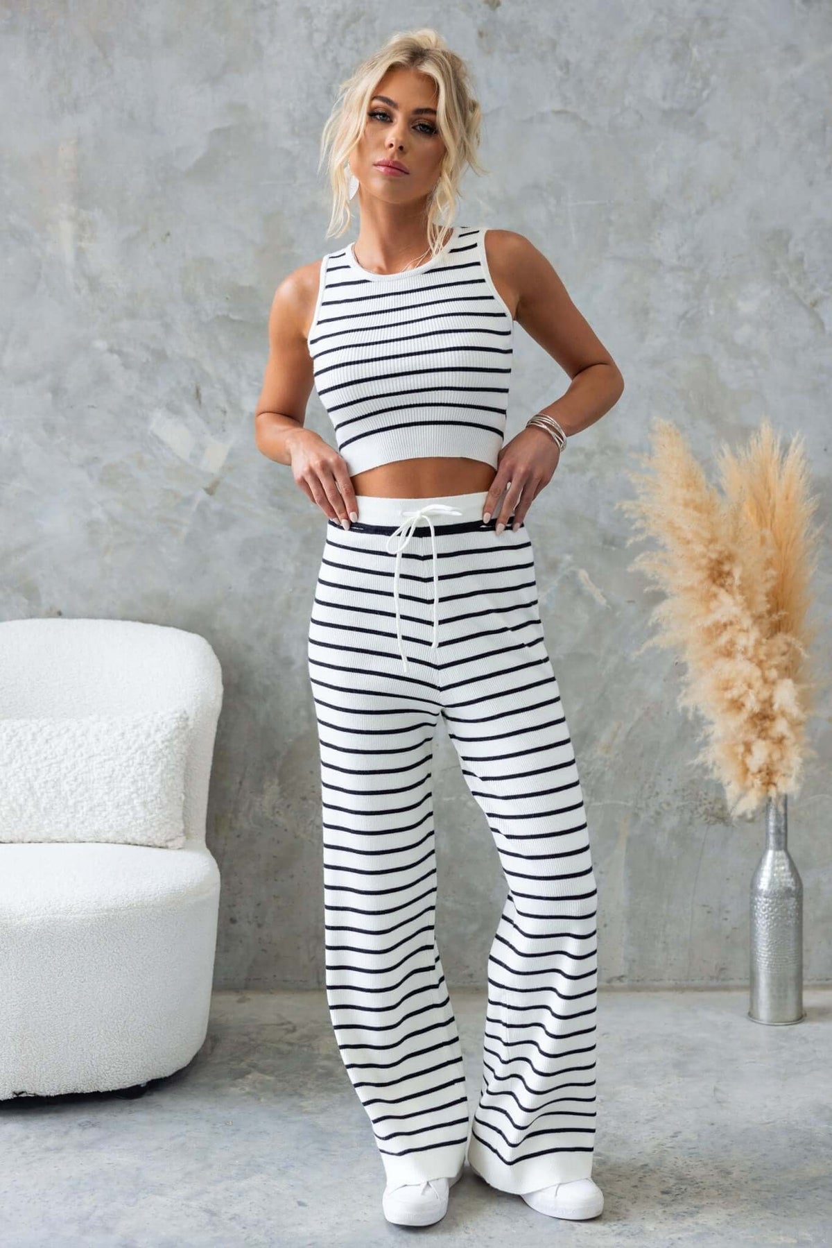 Model wearing Nowlan Top with striped pants, featuring a high neckline and ribbed knit material in a stylish setting.