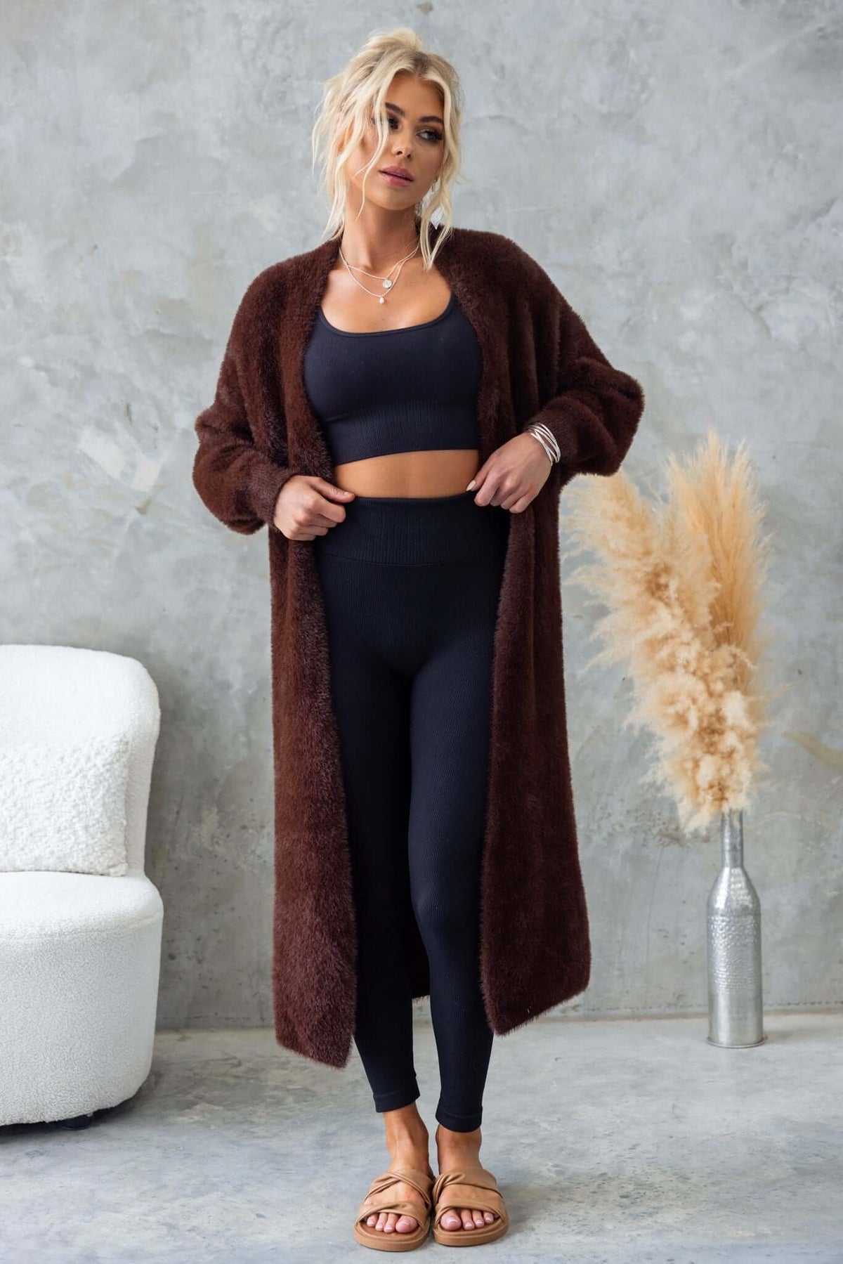 Model wearing a longline Salem Cardigan in brown, paired with black leggings and a crop top, showcasing a relaxed fit.
