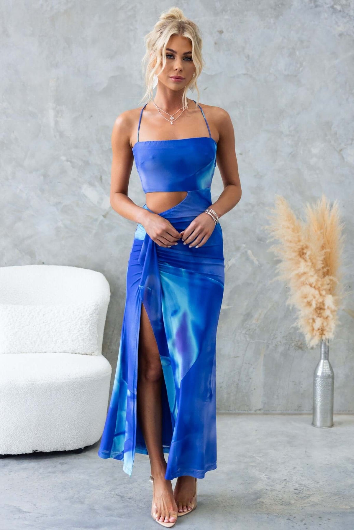 Orono Maxi Dress in blue with cut-out waist, adjustable straps, and front split, model styled elegantly.
