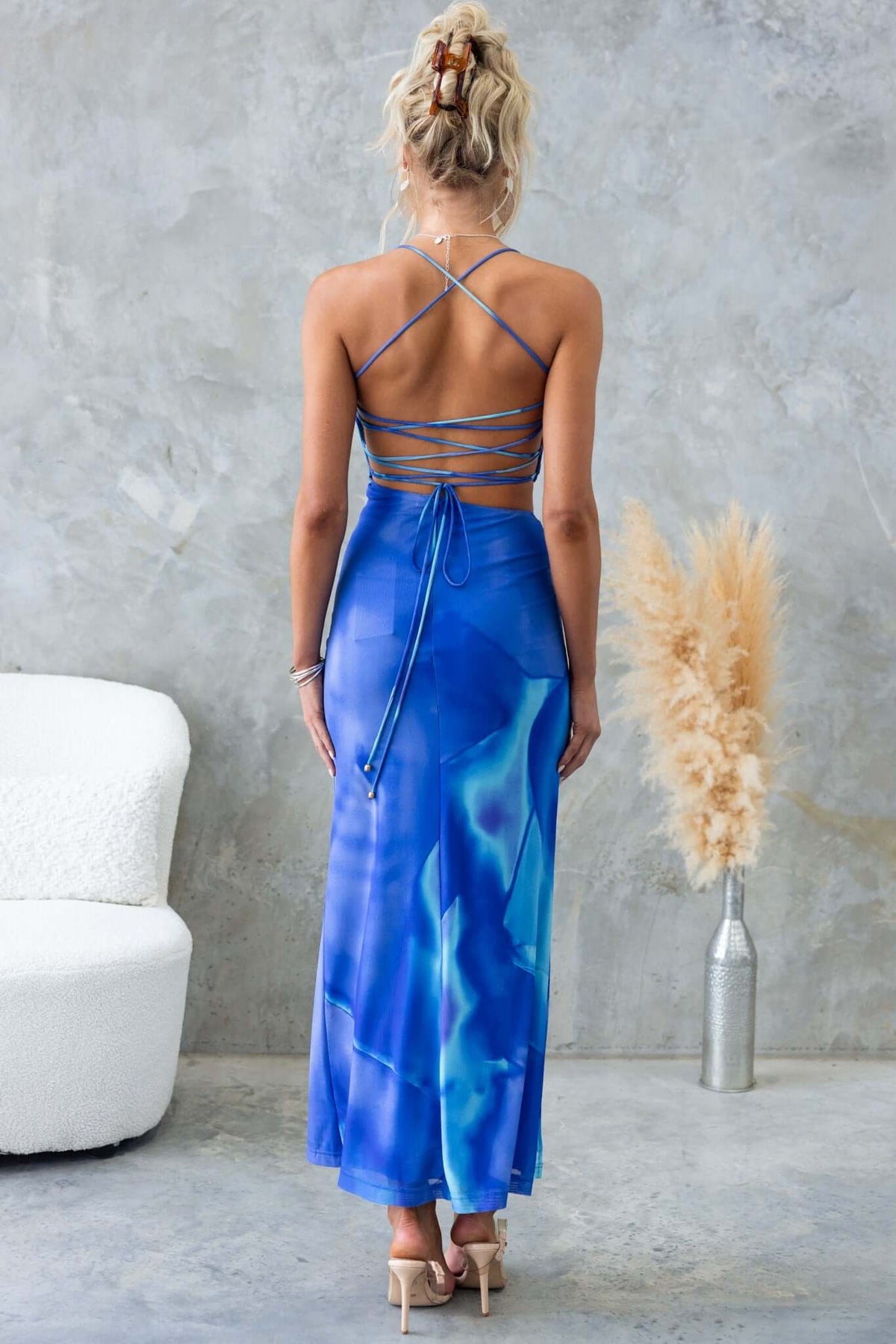 Back view of Orono Maxi Dress with adjustable straps and blue abstract print, stylishly paired in a modern setting.