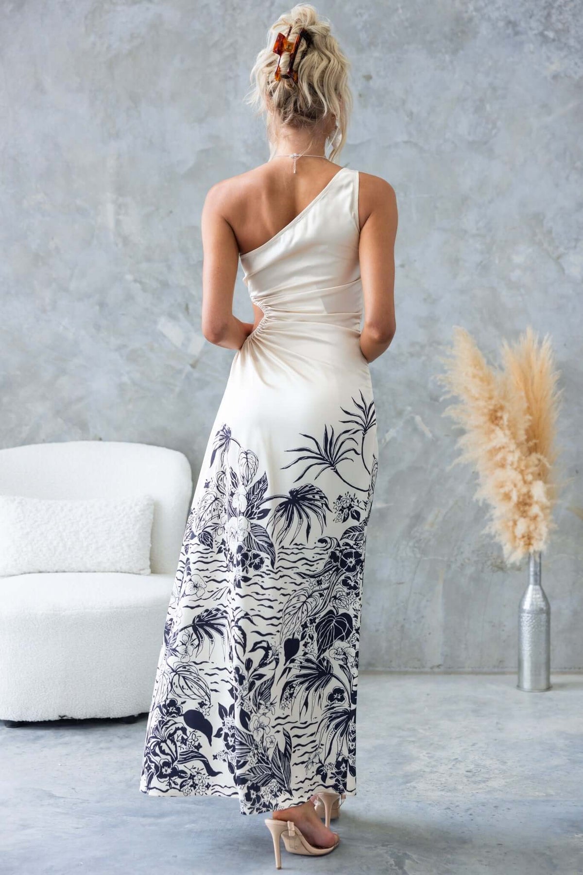 Back view of the Carey Maxi Dress featuring a floral print, one-shoulder neckline, and high front split.