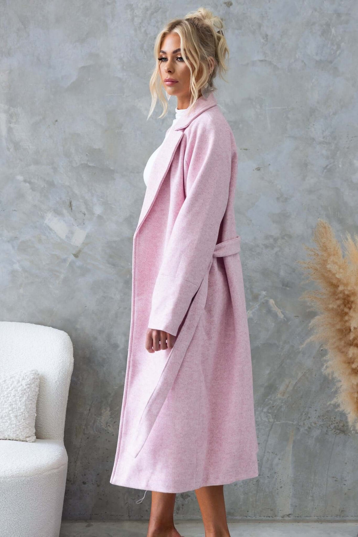 Jensen Coat in soft pink, featuring a longline fit, collar, lapel, and removable fabric tie, showcased by a model.