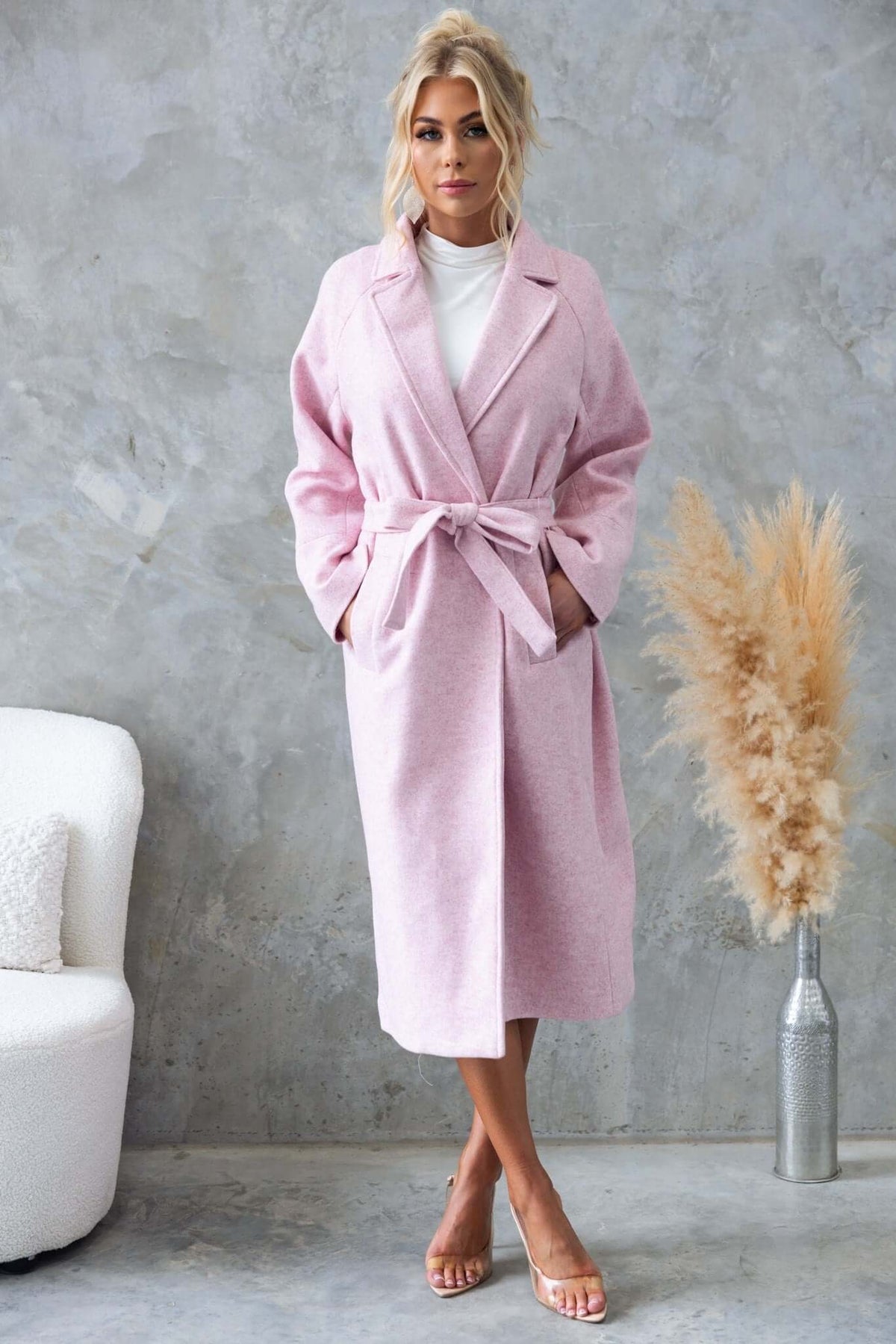 Jensen coat in soft pink, featuring longline fit, collar, pockets, and removable tie, worn by model in modern decor.