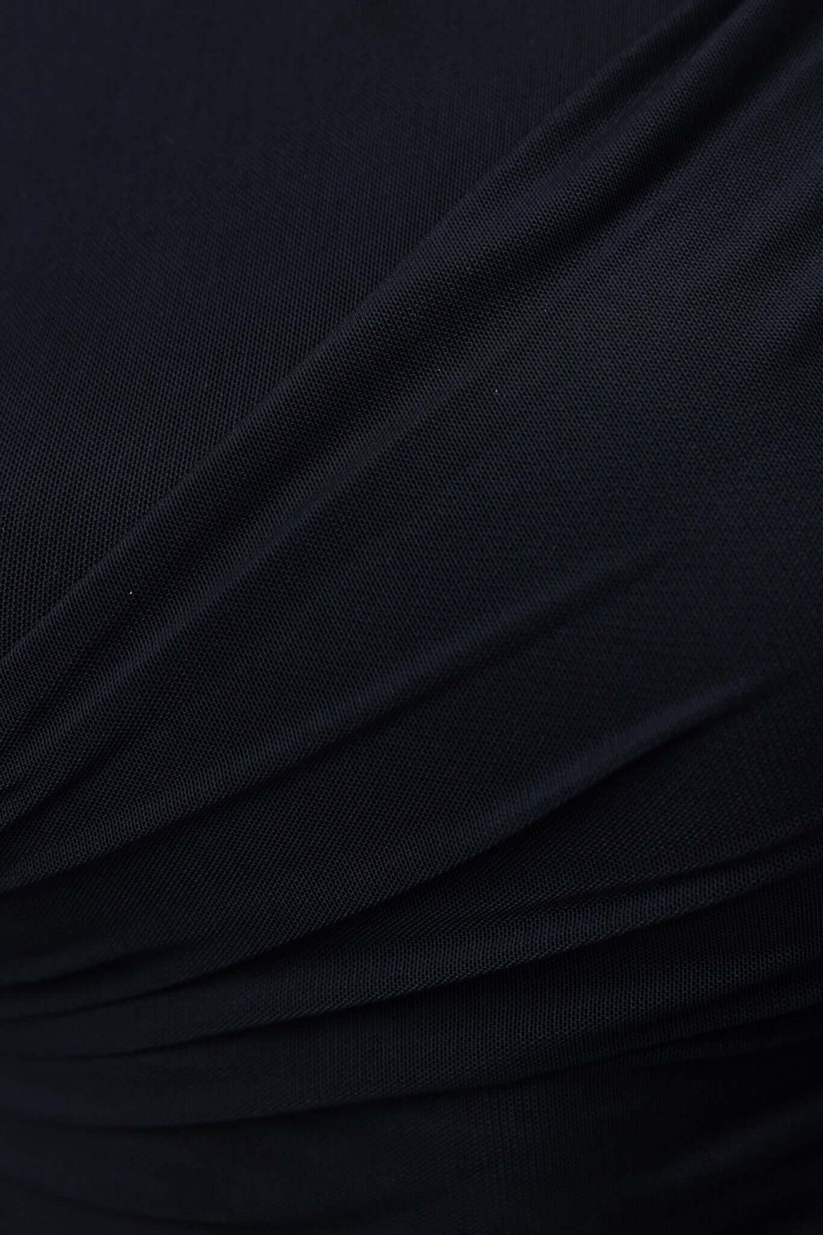 Close-up of the fabric texture of the black Cosmo Top featuring pleats and a smooth finish.