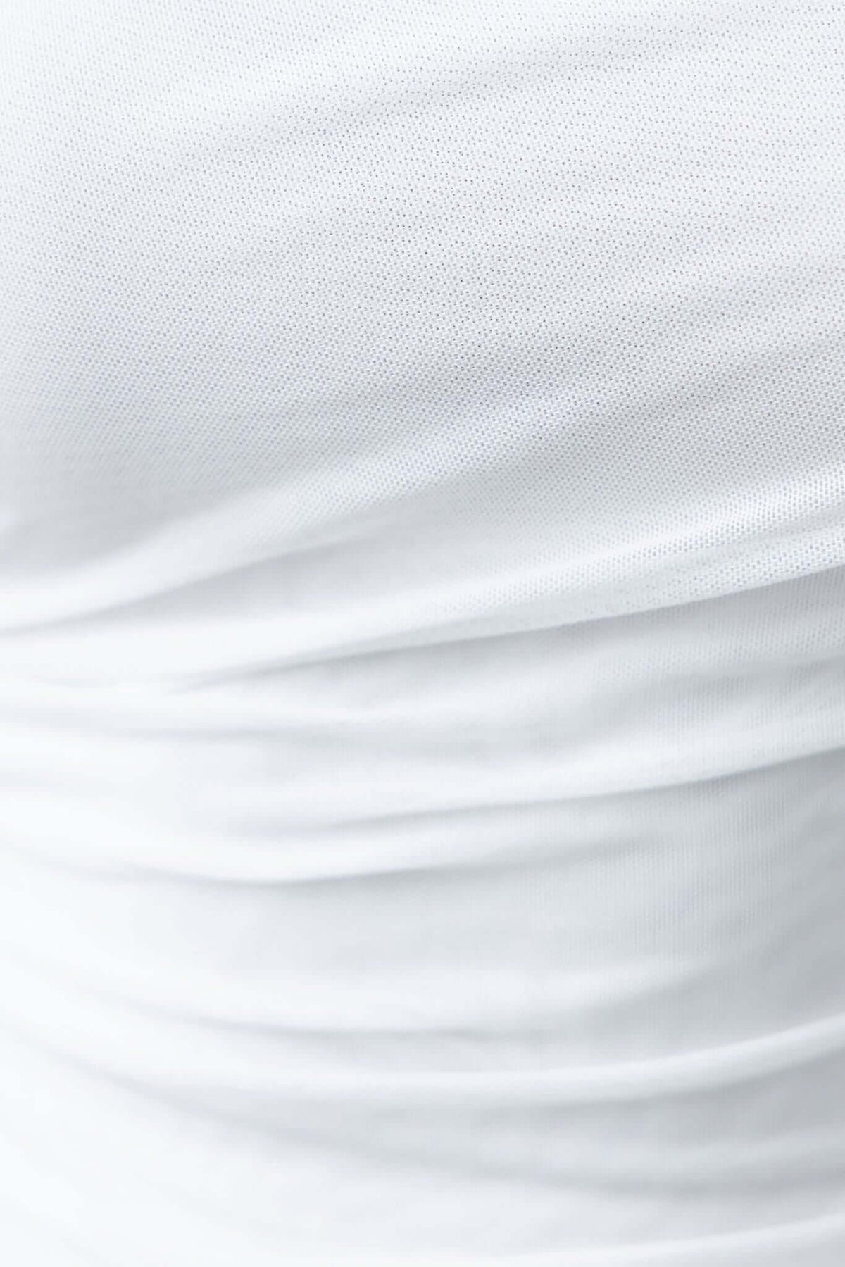 Close-up of the Cosmo Top's white fabric with soft pleats and texture, showcasing its stretch and quality.