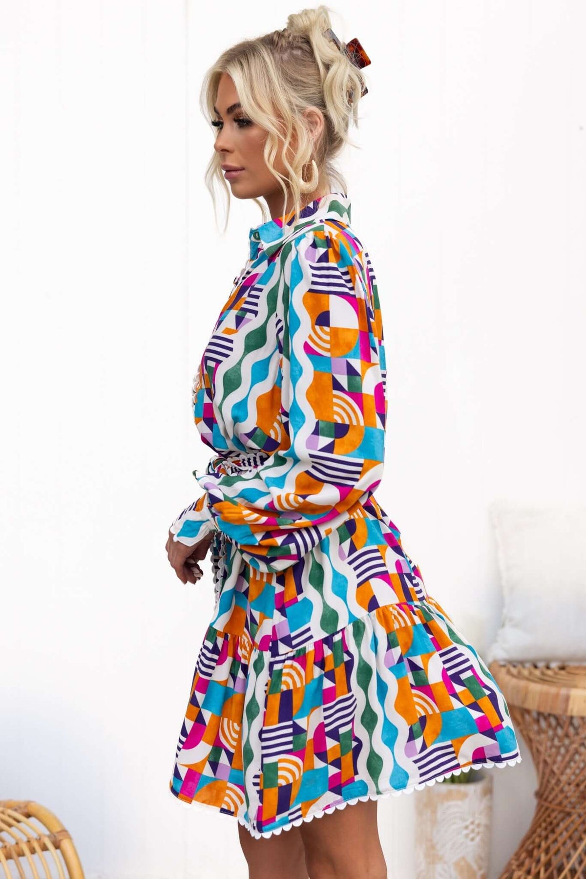 Model wearing the Bransley Dress featuring colorful geometrical patterns and a button-up collar.