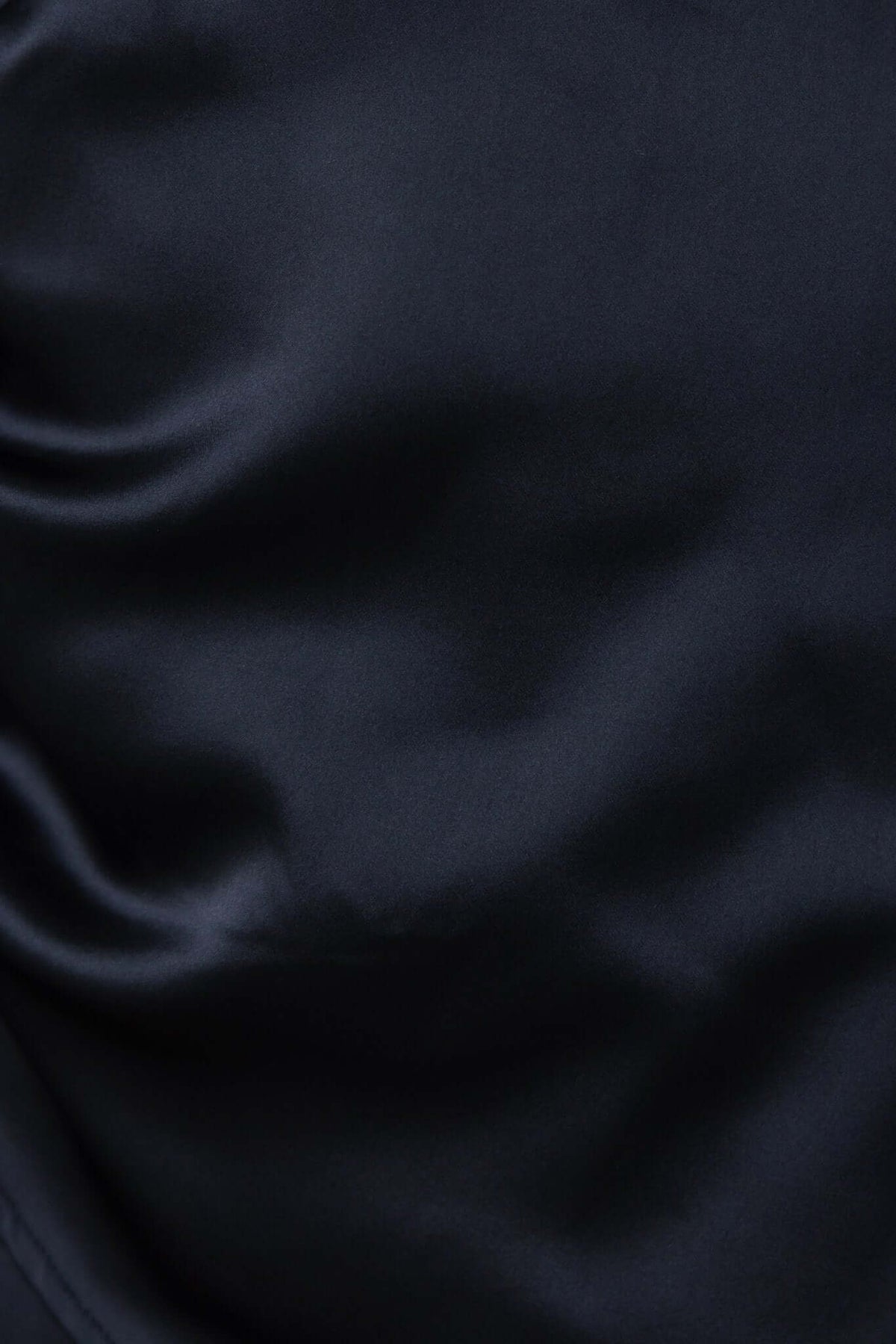 Close-up of luxurious black satin fabric with a smooth texture, showcasing the Vallejo Dress material.