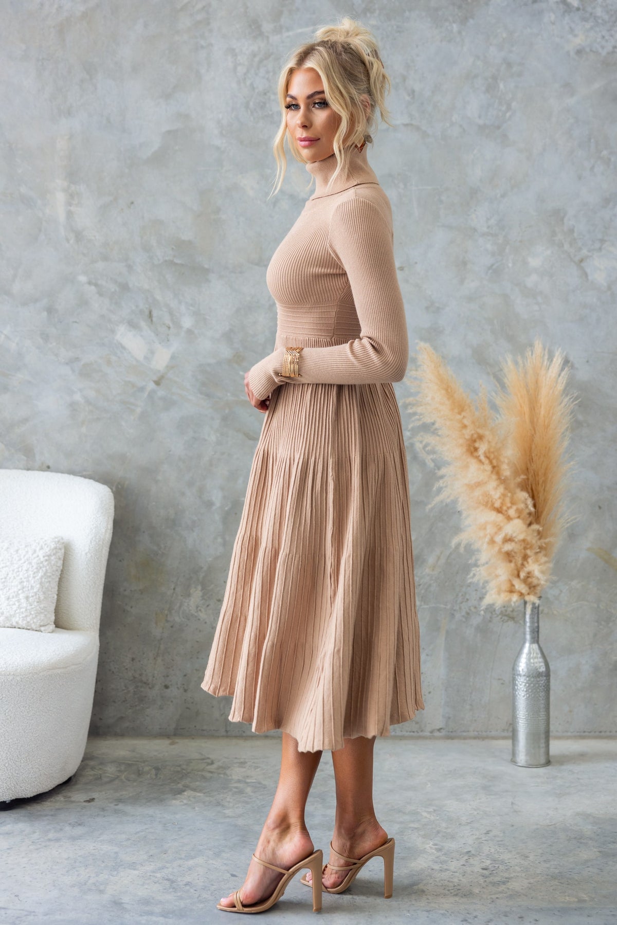Side view of a model wearing a beige Parkley Midi Dress with turtle neckline and ribbed knit material.