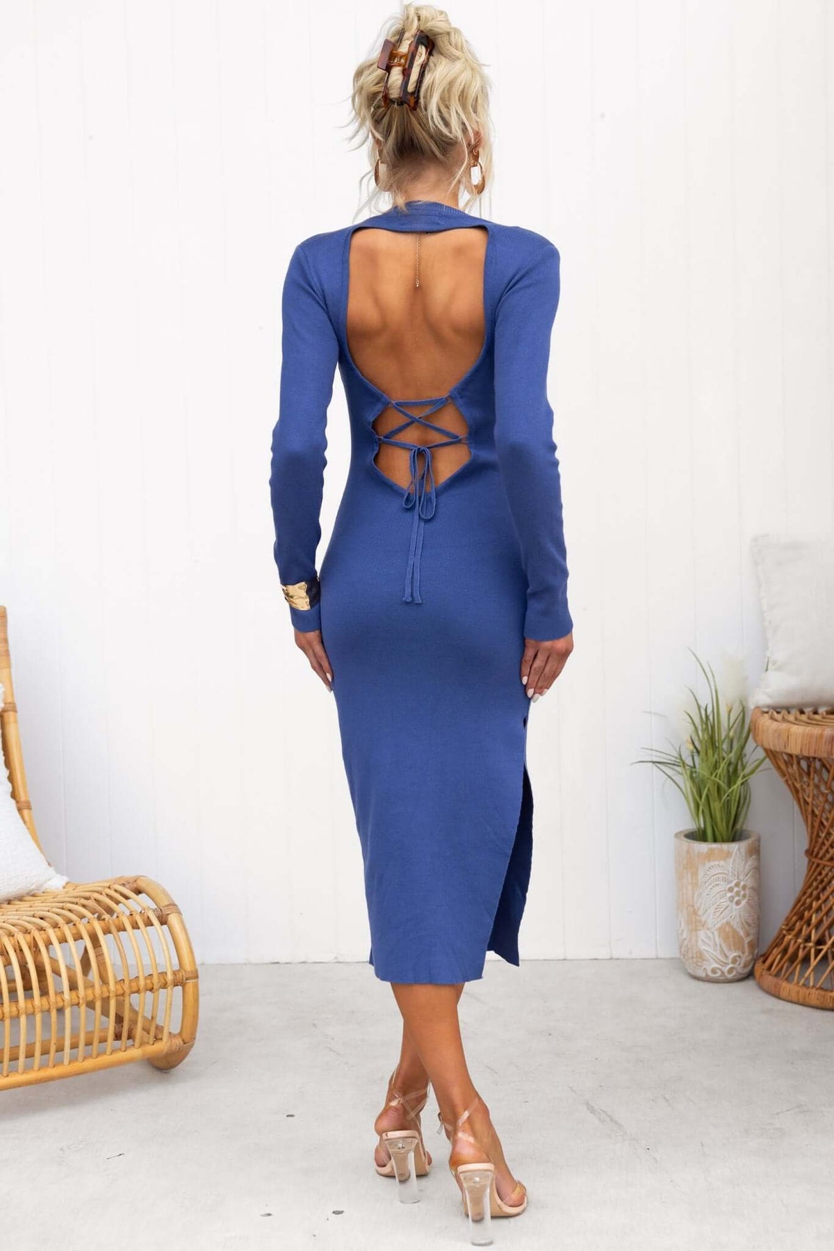 Back view of a woman wearing a blue Quita Midi Dress with open tie-back detail and side split.