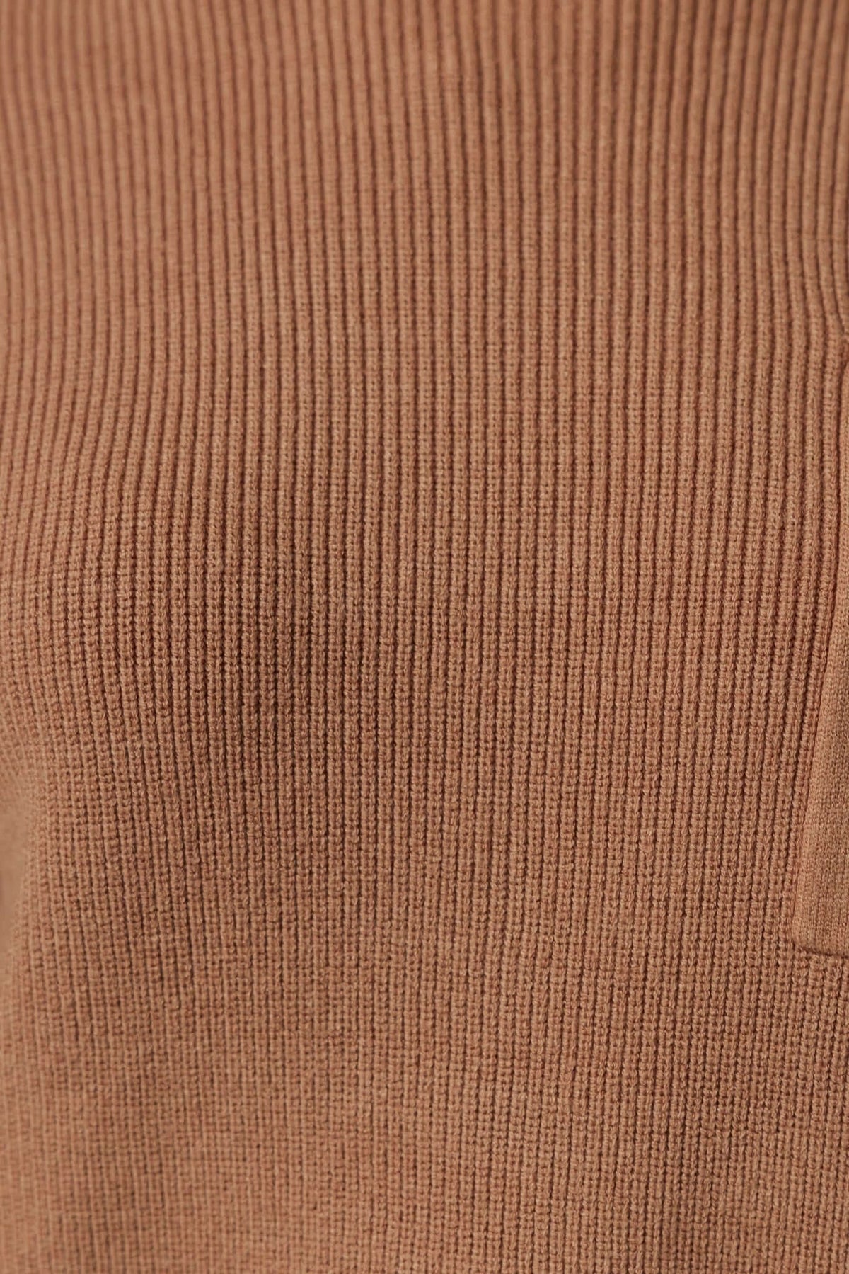 Close-up of the ribbed knit fabric of the Palladia Jumper in a warm brown shade, showcasing its stretch and texture.