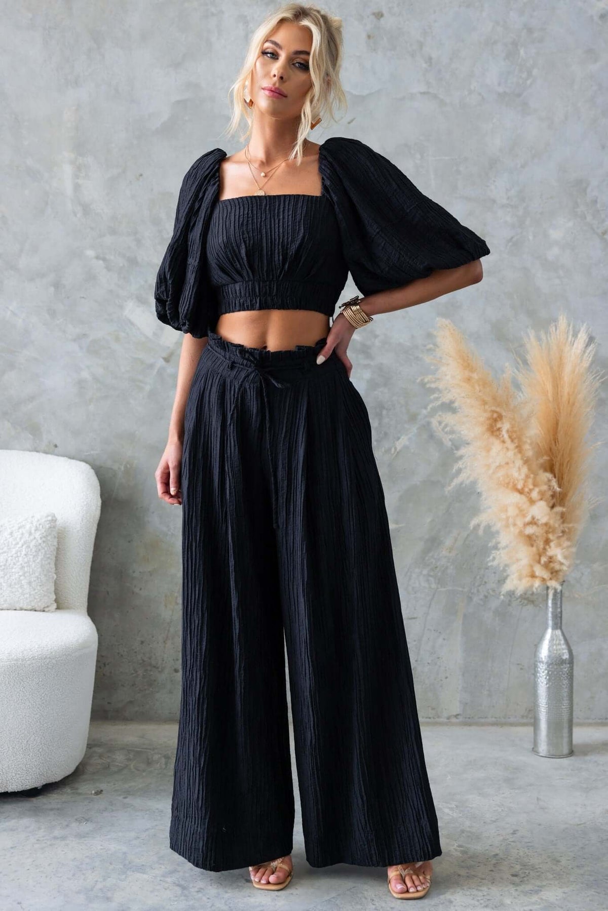 Stylish model wearing black Know Better Pants outfit featuring a textured, mid-high waist design with puff sleeves.
