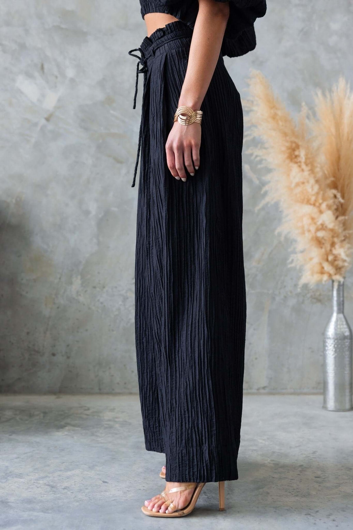Model wearing Know Better Black Pants with textured fabric, mid-high waist, side view showcasing removable tie and pockets.