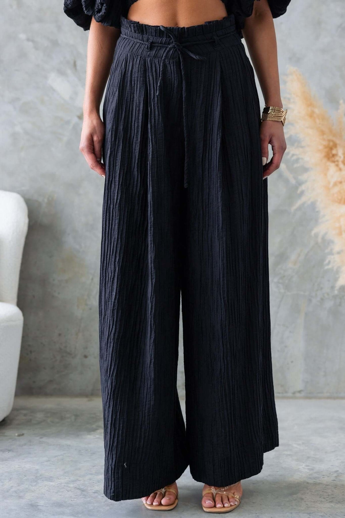Black mid-high waist pants with removable tie, textured fabric, and pockets, perfect for a stylish casual look.