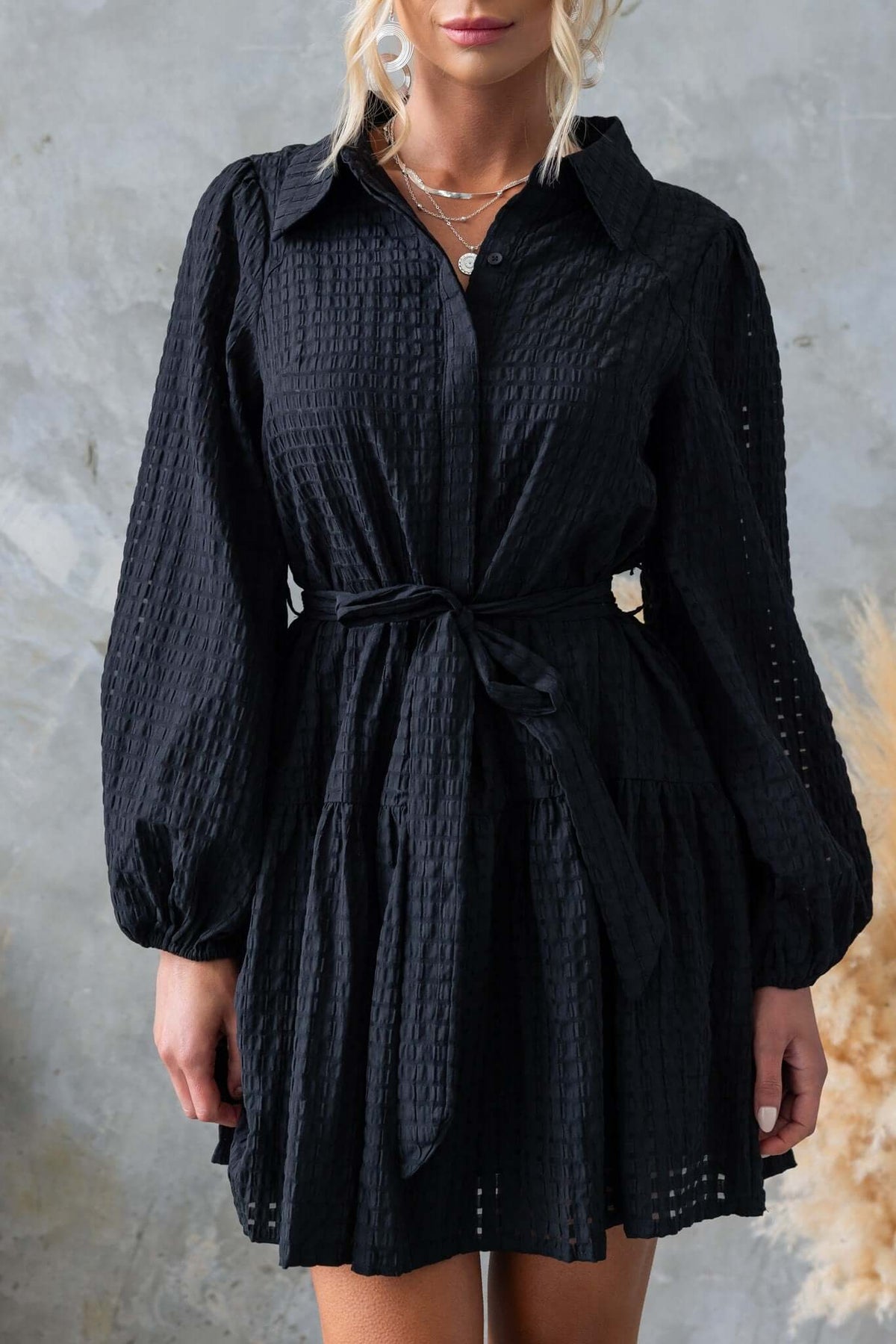 Cottee Dress in black with button-up front, elastic sleeves, and removable tie. Stylish and comfortable with pockets.