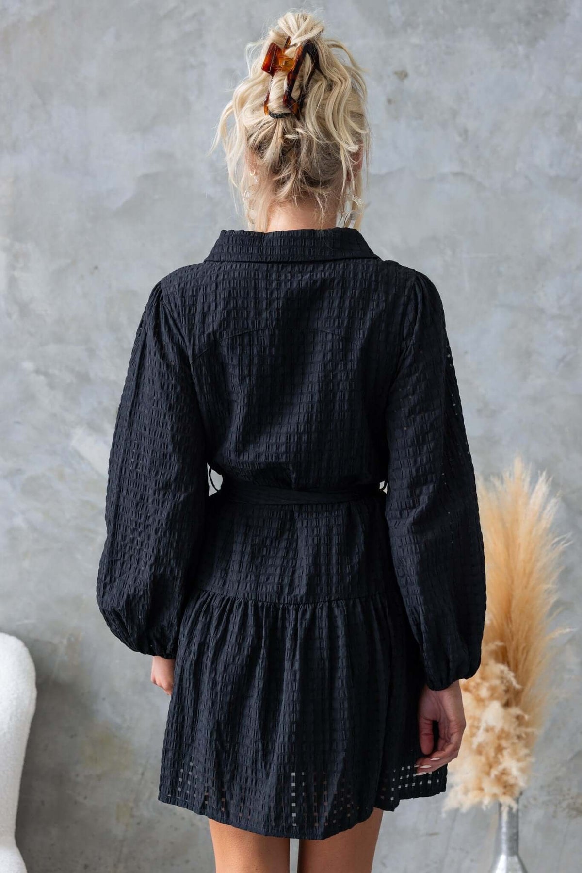 Back view of the Cottee Dress in black, featuring a collar, button-up front, and elastic sleeves.