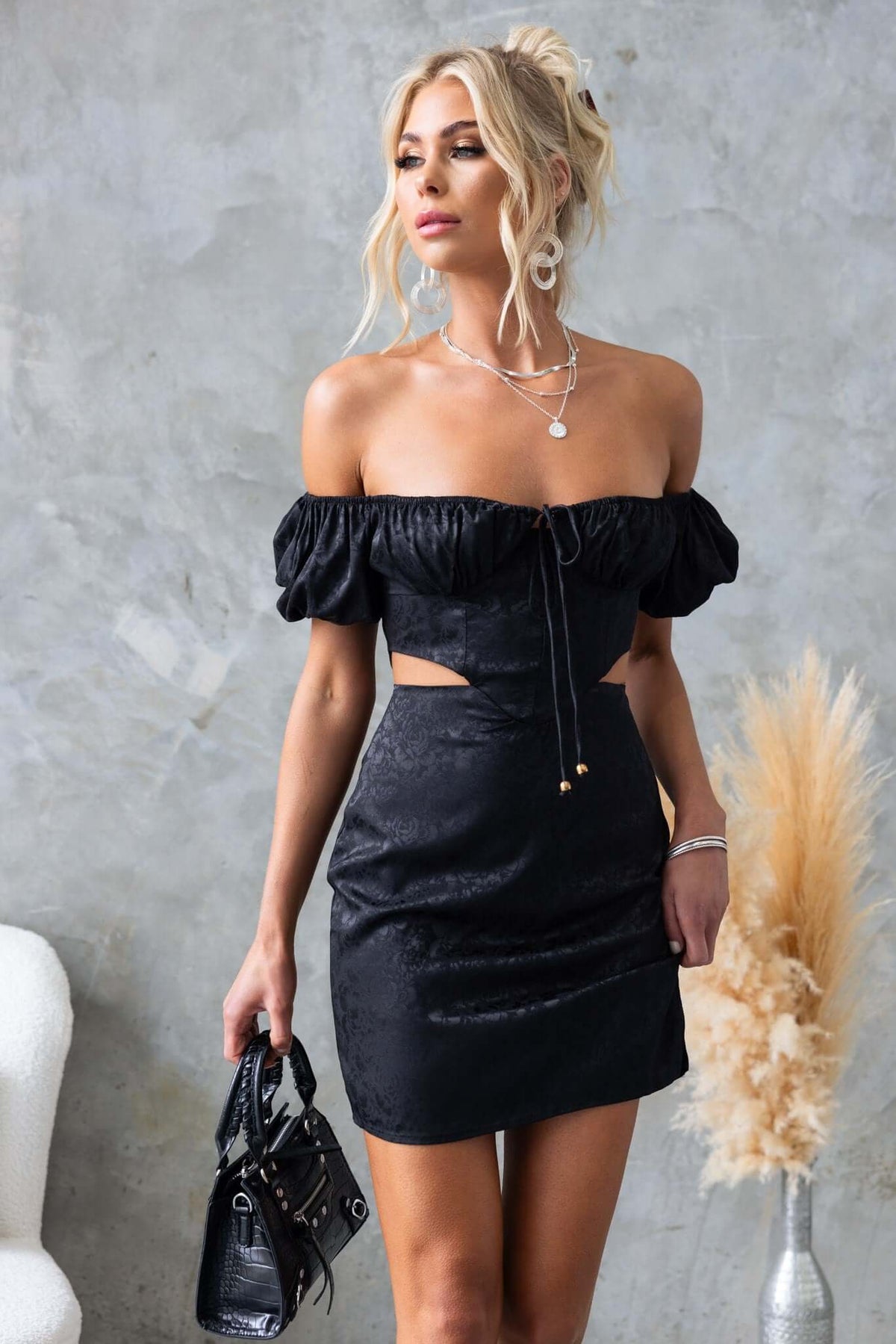 Stunning black Dalma dress with elastic sleeves, cut-out waist, and front split for a chic, satin look.
