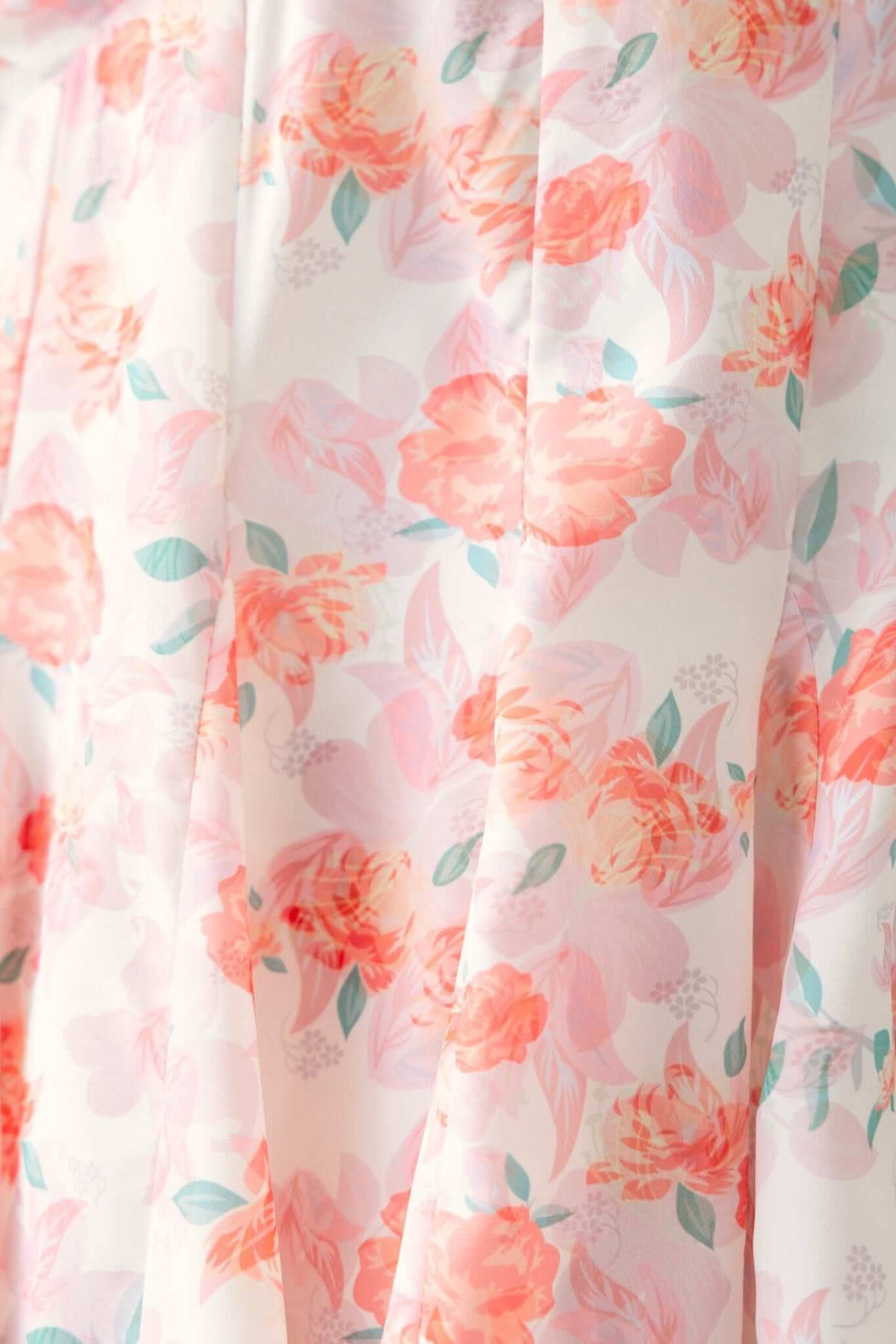 Close-up of floral fabric in soft pink hues, featuring peach roses and green leaves for the Feel Good Dress.