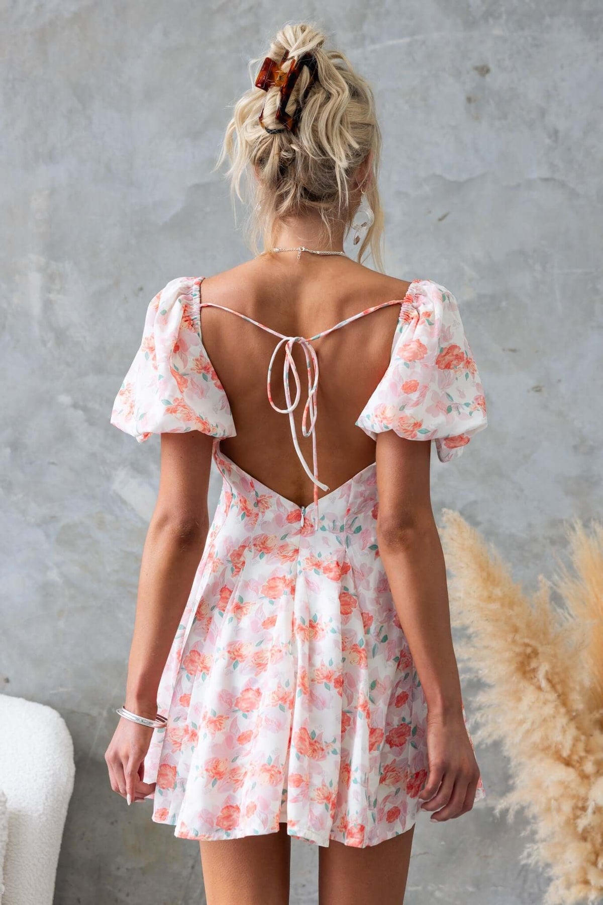 Back view of the Feel Good Dress featuring floral print, puff sleeves, and a low-cut back with tie detail.