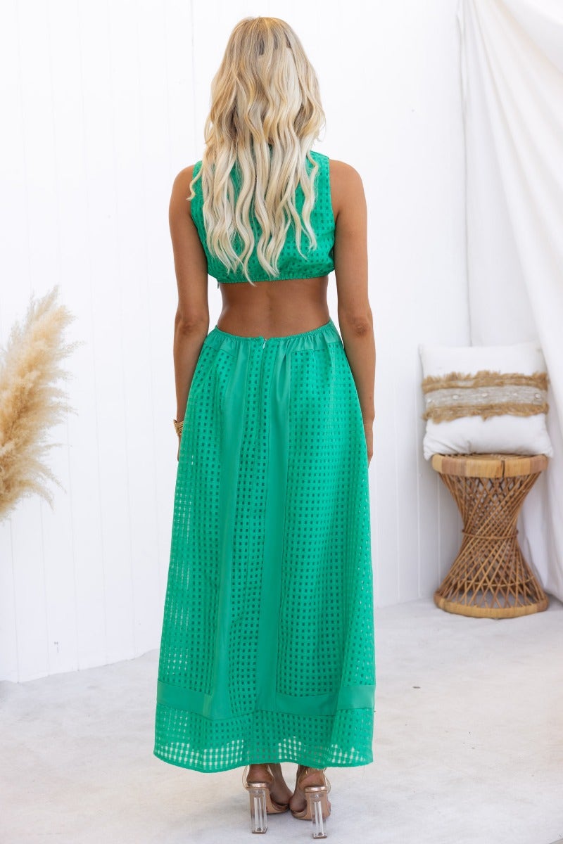 Back view of a model wearing a green textured Tamzin Maxi Dress with a high neckline and cut-out waist.