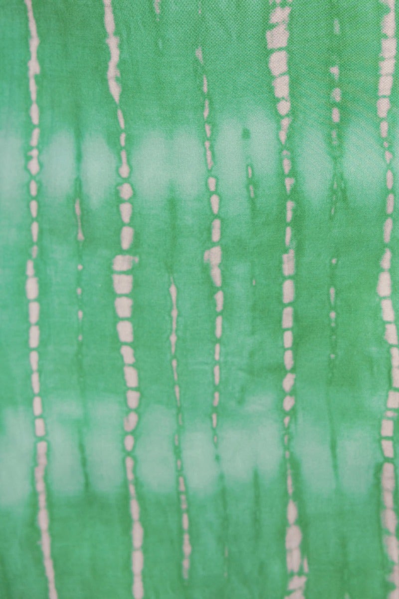 Close-up of green fabric featuring a tie-dye pattern with vertical white stripes.