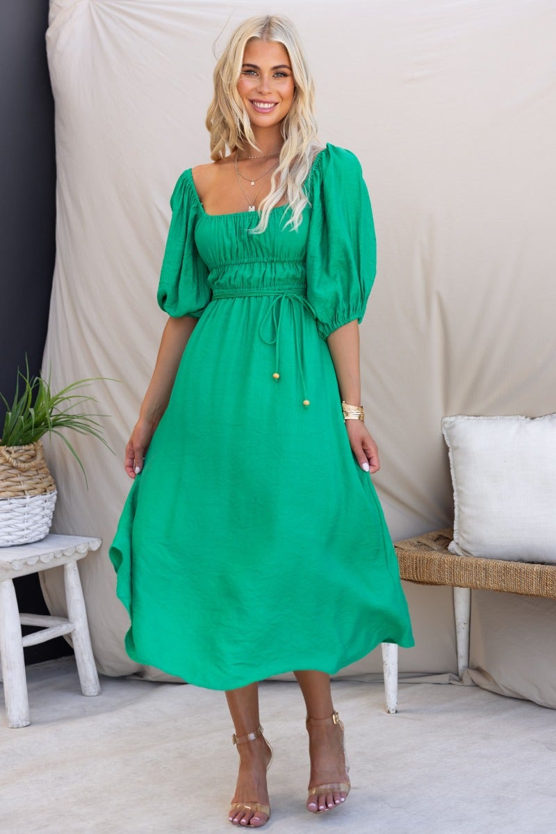Model wearing a green Qove midi dress with puff sleeves and removable tie, styled for summer fashion.