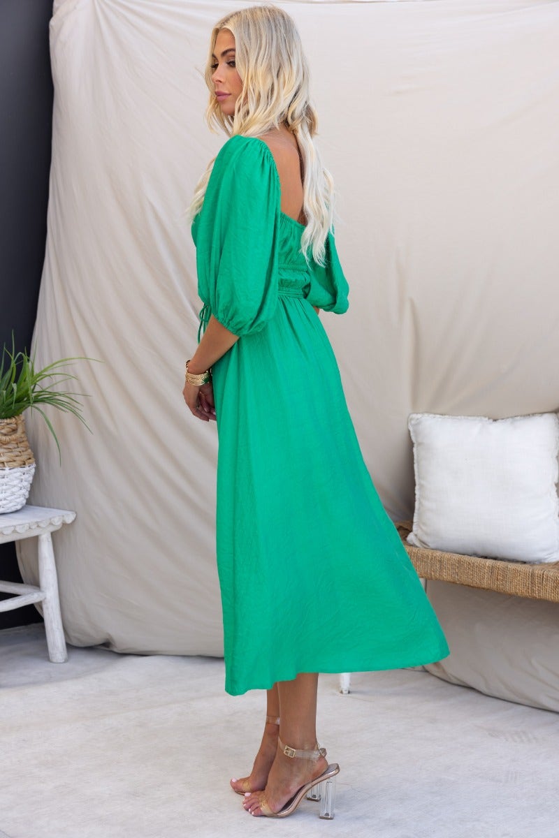 Elegant green Qove midi dress featuring elastic neckline, puff sleeves, and removable tie detail, lined to mid-thigh.