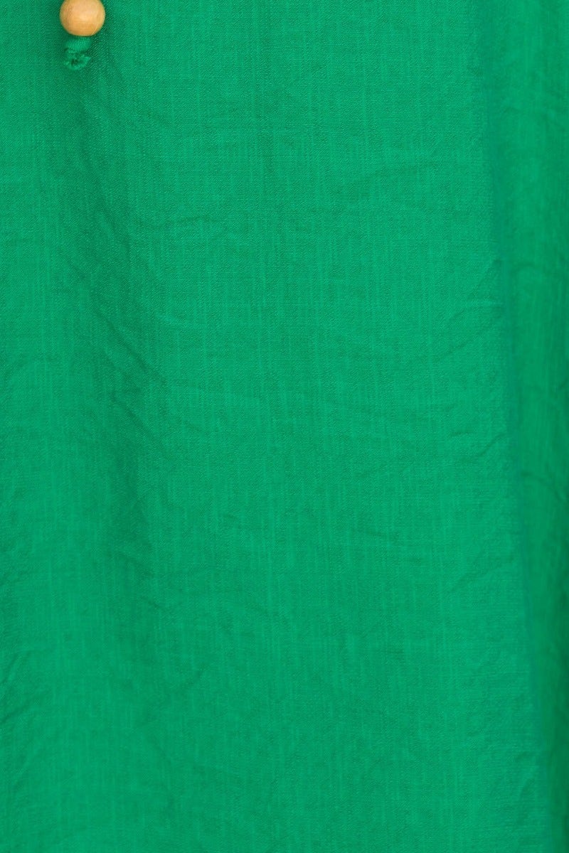 Close-up of Qove midi dress fabric in vibrant green with wooden button detail.