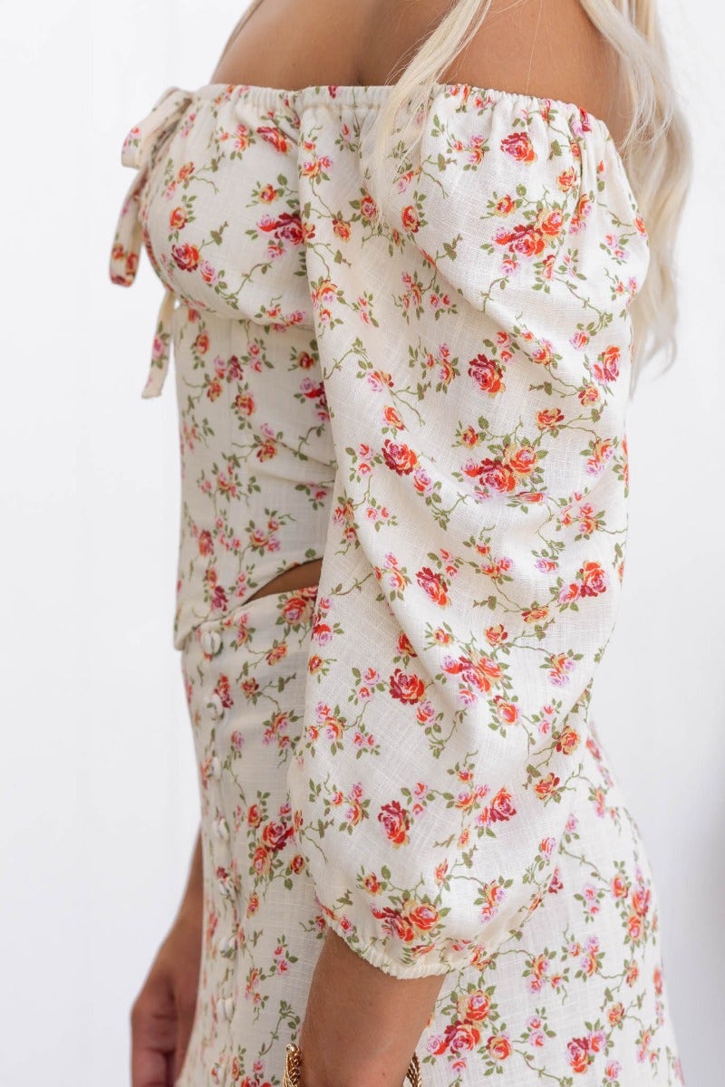 Rubie Top with floral design; off-shoulder style, tie detail, and elastic sleeves in a light linen blend.