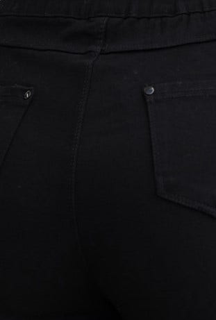 Black jeggings close-up showing faux back pockets and stretchy mid-high waist fit.