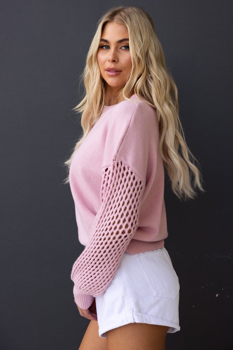Model wearing a pink ribbed knit Verny jumper with open weave sleeves styled with white shorts.