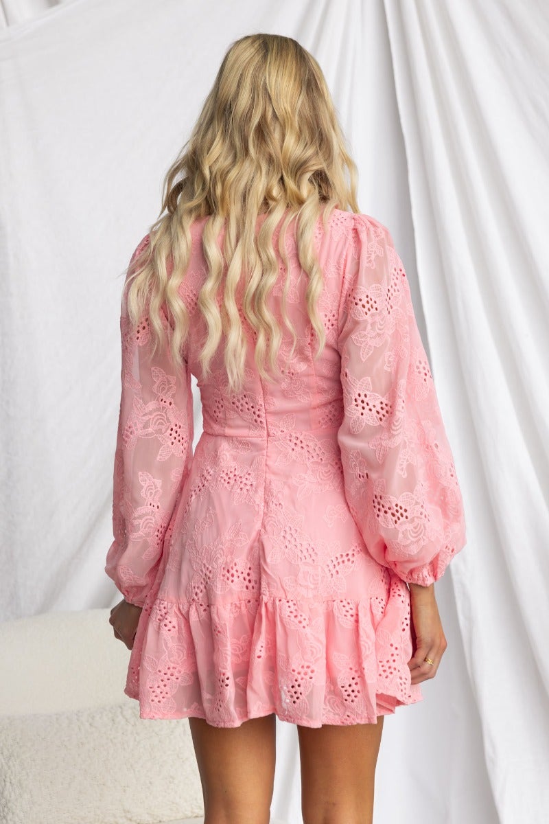 Back view of the Pinolo Dress in pink Anglaise material featuring puff sleeves and a flared hem.