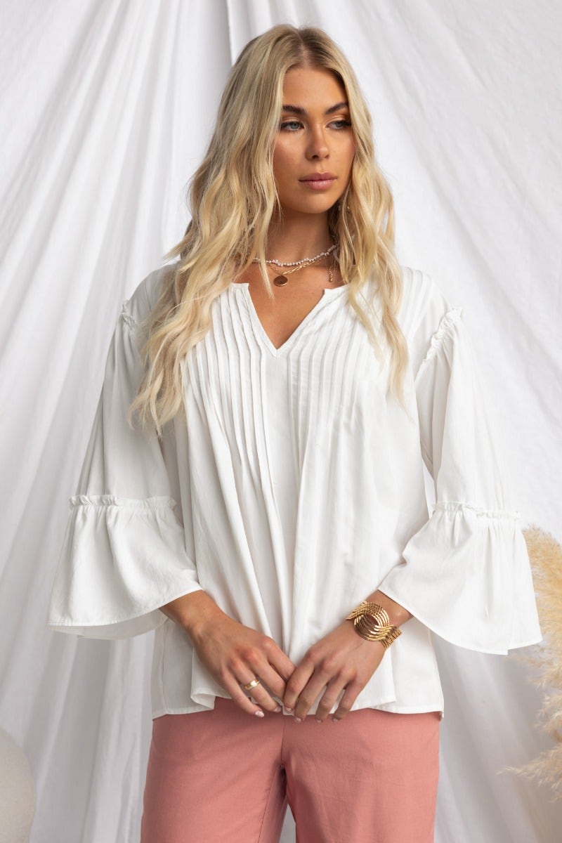 Stylish woman wearing a white cotton blend Cove Top with pleat detail and relaxed fit.