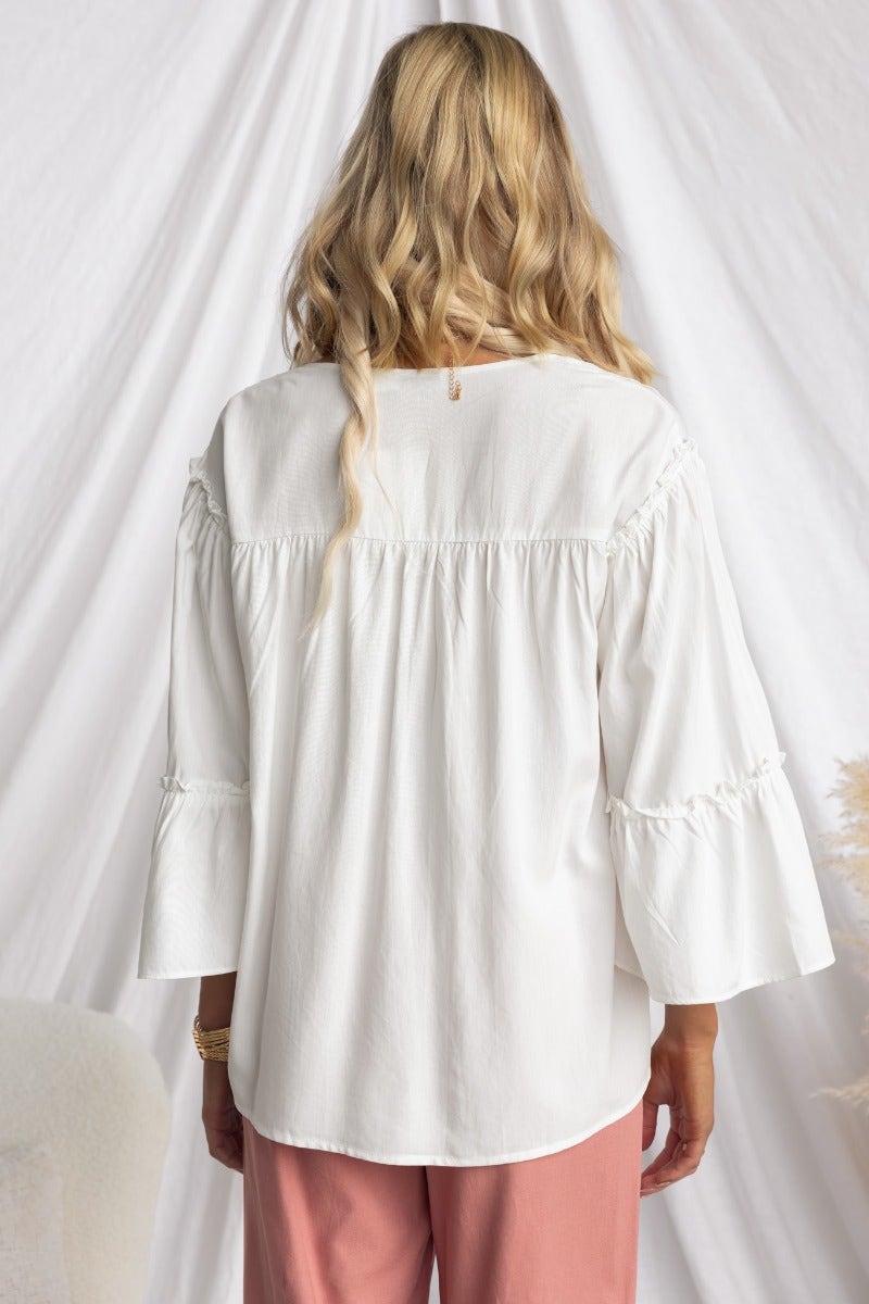 Back view of a model wearing a white cotton blend Cove Top with pleat detail and relaxed fit.