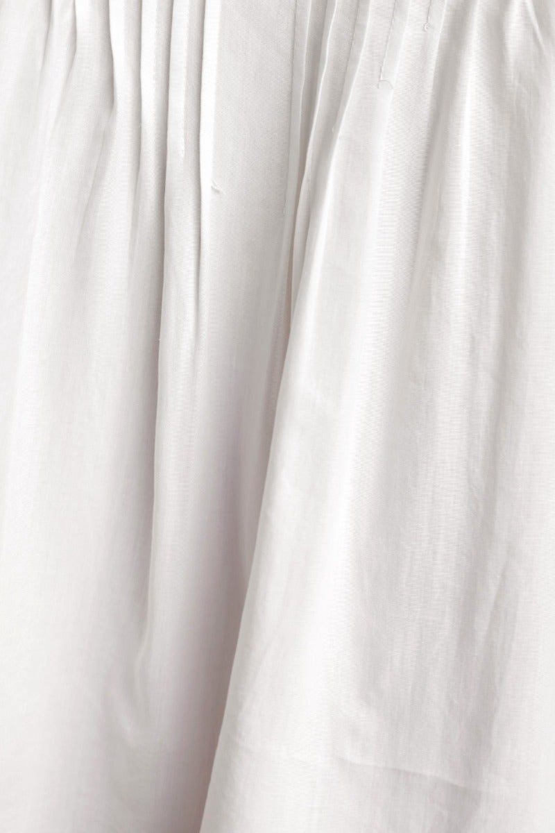 Close-up of a white cotton blend fabric showcasing pleat details, ideal for relaxed fit garments.