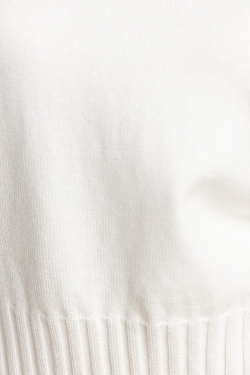 Close-up of Melika Jumper showcasing soft ribbed knit texture in ivory color, featuring stretch material and high neckline.