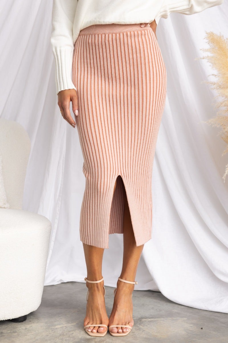 Viloa Midi Skirt in ribbed knit with elastic waistband and front split, styled with a white sweater and sandals.