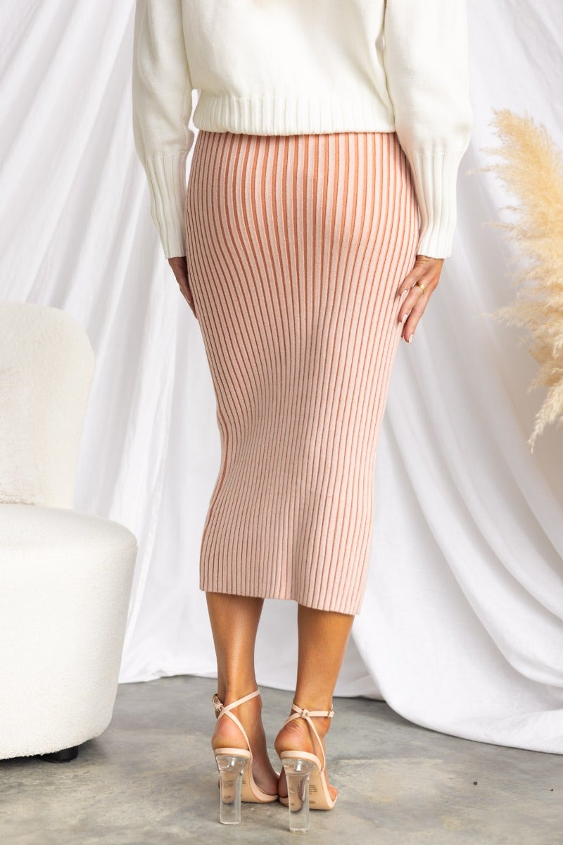 Back view of Viloa Midi Skirt with ribbed knit design, paired with a cozy sweater and heels, set in a stylish interior.
